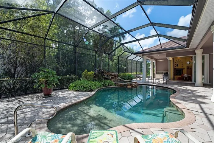 View of pool with screened enclosure and a patio area