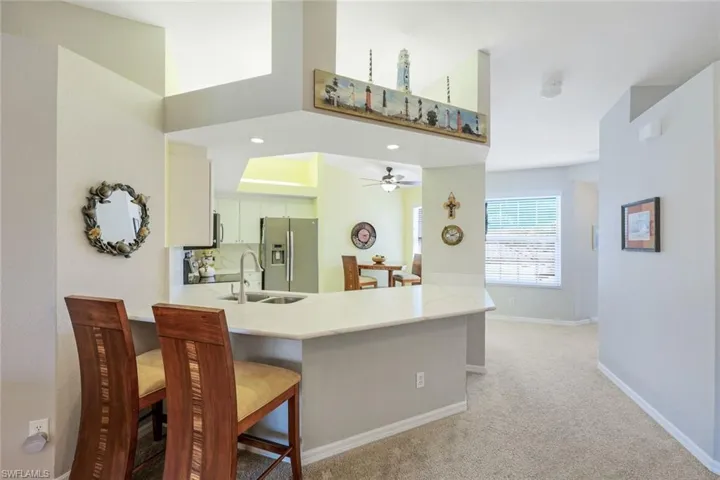 Bright and open kitchen with counter height seating and dinette area, stainless steel appliances, and pantry.