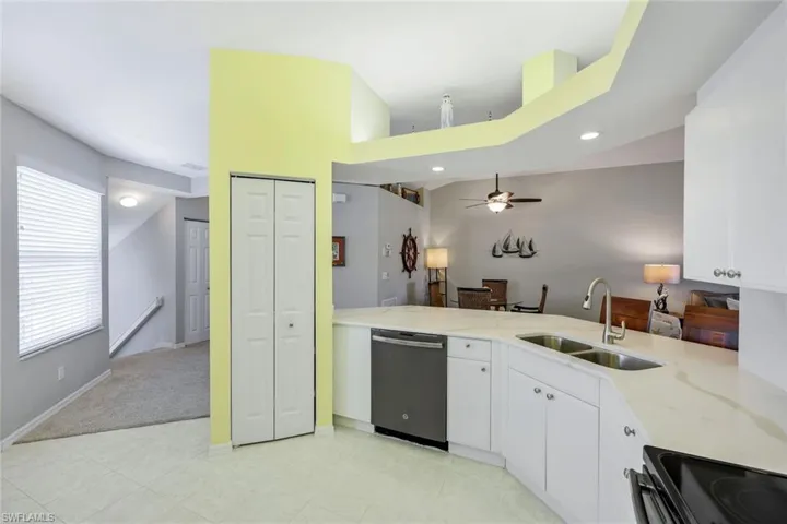 Spacious and open kitchen with brand new (2025) quartz counter tops and backsplash with marble look, pantry, counter height seating, double bowl kitchen sink, and tile floor.