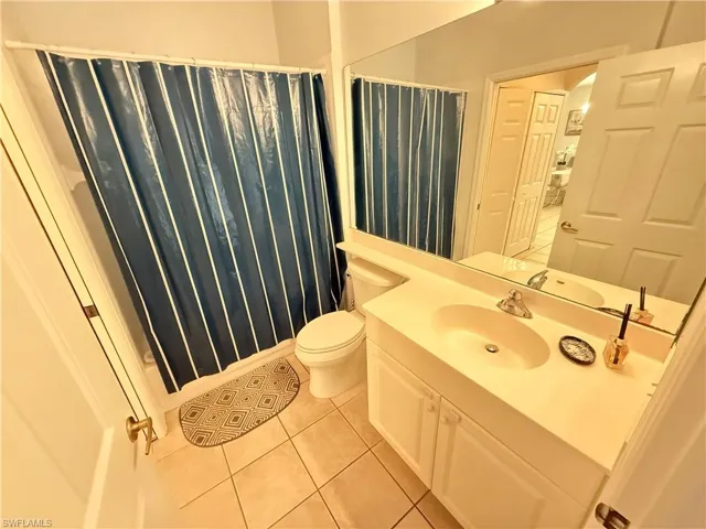 Full bathroom with vanity, light tile patterned floors, and a shower with curtain