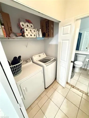 Laundry area featuring light tile patterned floors and independent washer and dryer