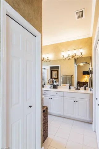 Bathroom featuring double vanity, ornamental molding, and tile floors