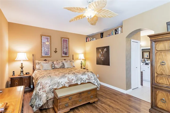 Bedroom with hardwood / wood-style flooring, ceiling fan, and ensuite bath