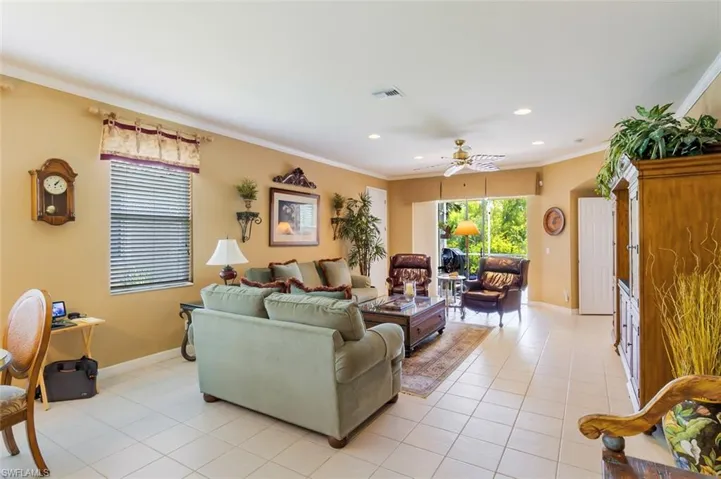 Tiled living room with ornamental molding and ceiling fan