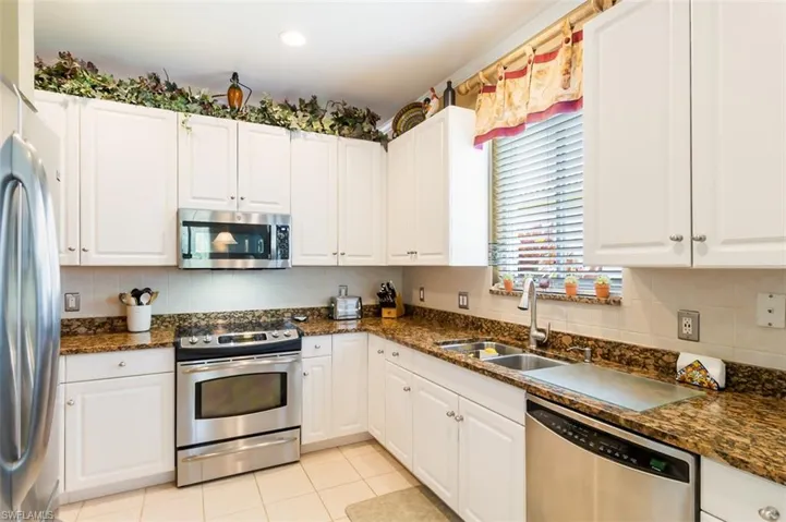 Kitchen featuring stainless steel appliances, sink, white cabinetry, and tasteful backsplash