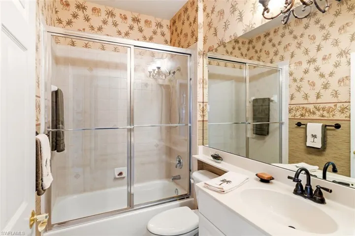 Full bathroom featuring shower / bath combination with glass door, vanity, and toilet
