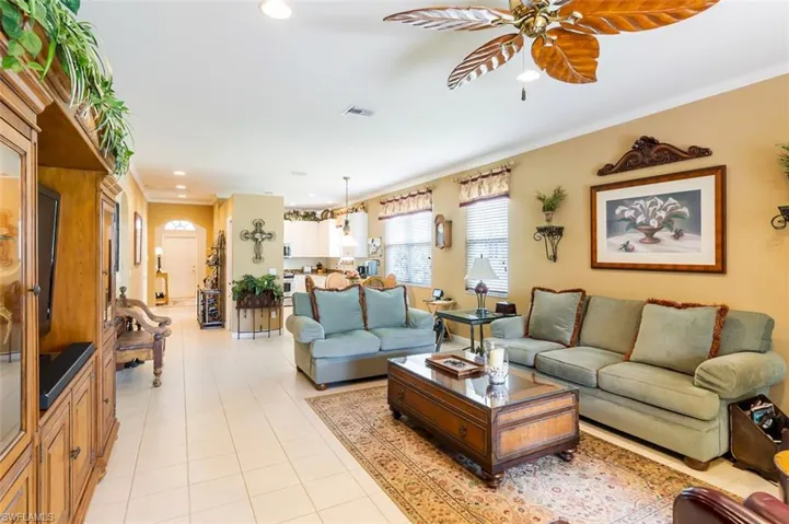 Tiled living room with ceiling fan and crown molding