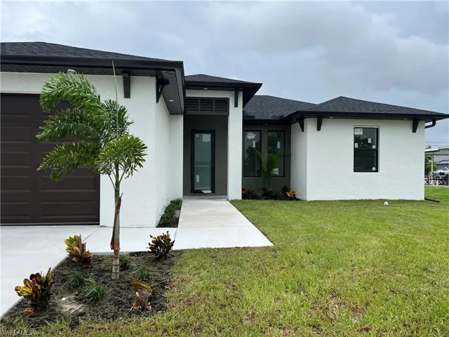 View of exterior entry featuring a garage and a yard