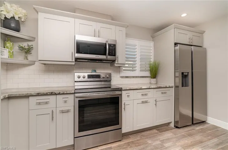 granite counters, white cabinets, light wood style tile, Stainless appliances