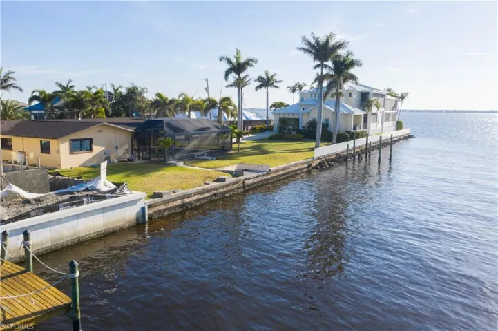 Dock area featuring glass enclosure, a water view, a lawn, and a residential view