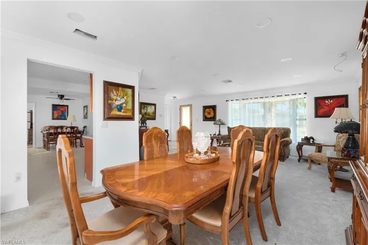 Dining area featuring ornamental molding, visible vents, and light colored carpet
