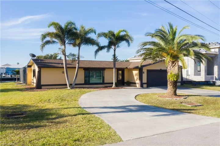 View of front facade featuring stucco siding, a garage, a front lawn, and curved driveway