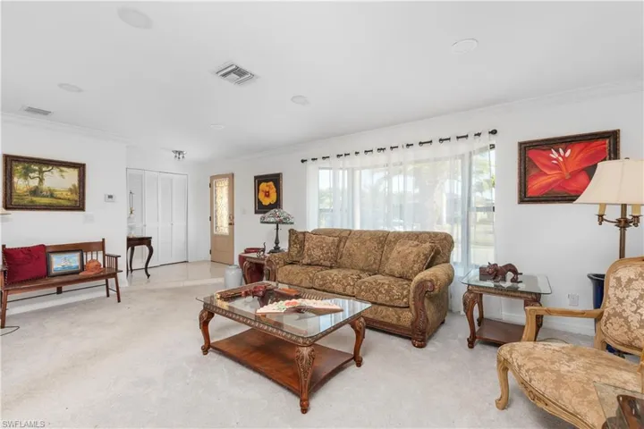 Living area featuring ornamental molding, light carpet, and visible vents