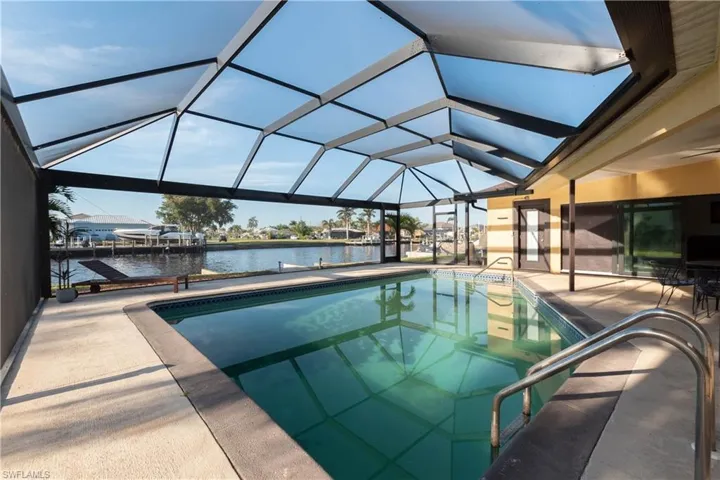 Outdoor pool featuring a water view, glass enclosure, and a patio
