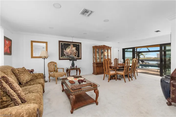 Living room featuring carpet floors, visible vents, and crown molding