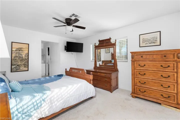 Bedroom with baseboards, visible vents, a ceiling fan, and light colored carpet