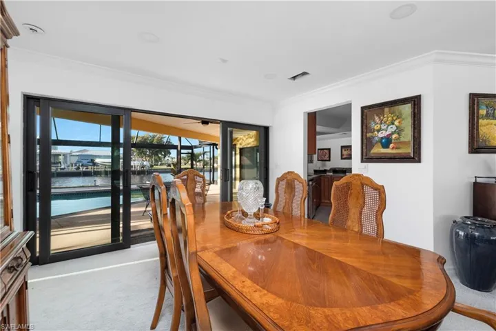 Carpeted dining space featuring ceiling fan and crown molding
