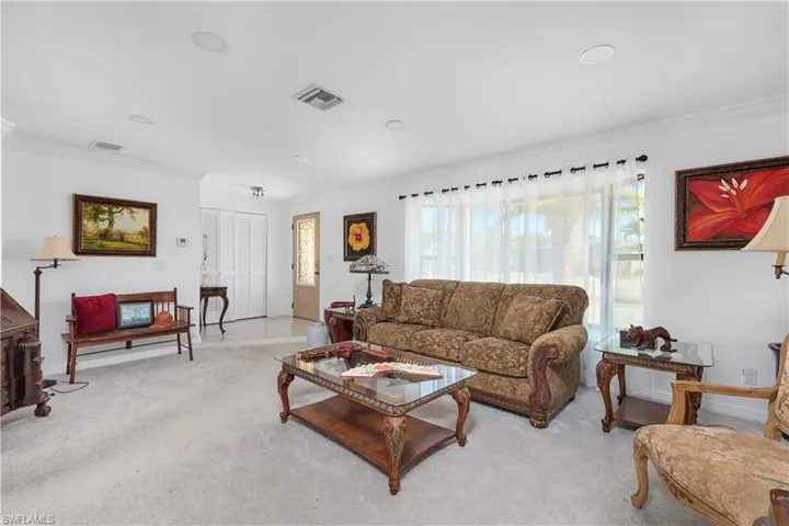 Living area with ornamental molding, light colored carpet, and visible vents