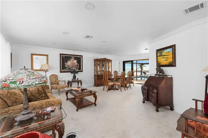 Living room with light carpet, visible vents, and crown molding