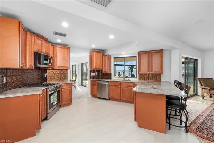 Kitchen with visible vents, a peninsula, stainless steel appliances, a sink, and a breakfast bar area