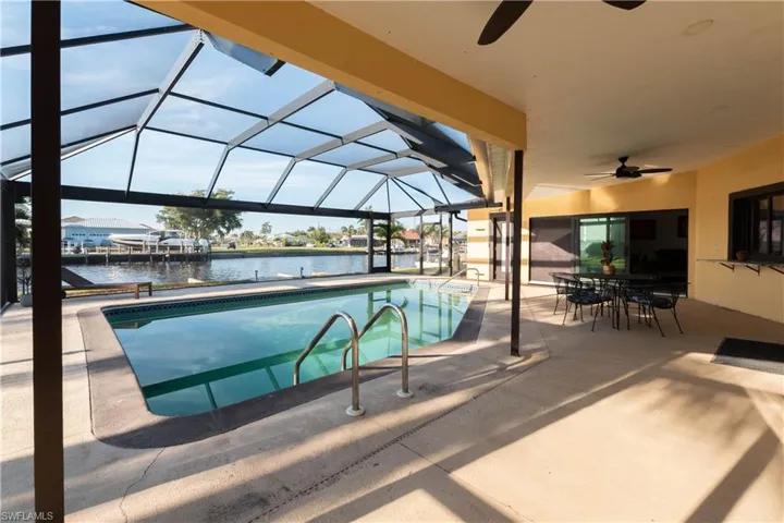 Pool with a lanai, a water view, a patio, and a ceiling fan