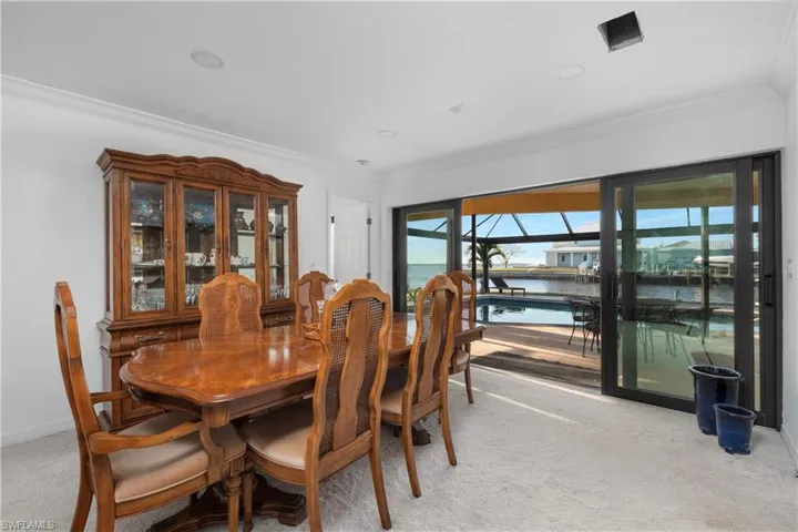Dining space featuring light colored carpet, a water view, baseboards, and ornamental molding