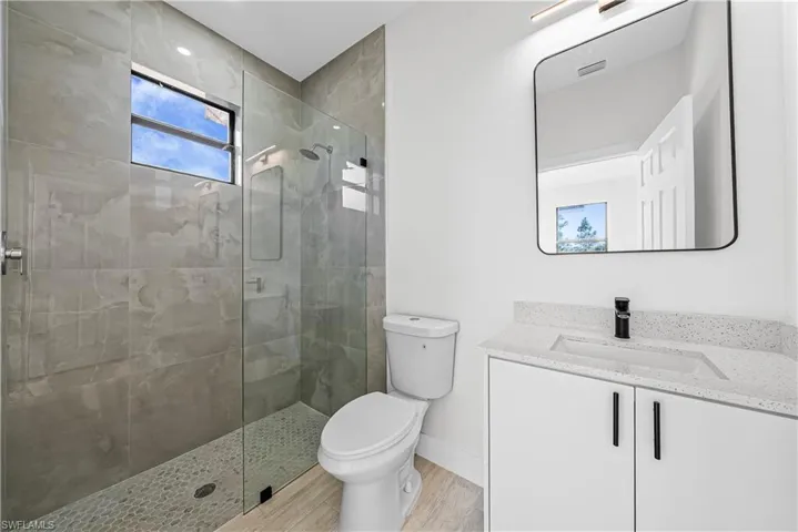 Bathroom with a walk in shower, vanity, and light wood-type flooring