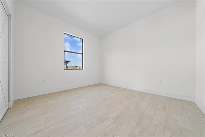 Unfurnished bedroom featuring vaulted ceiling, light wood-style floors, and a closet