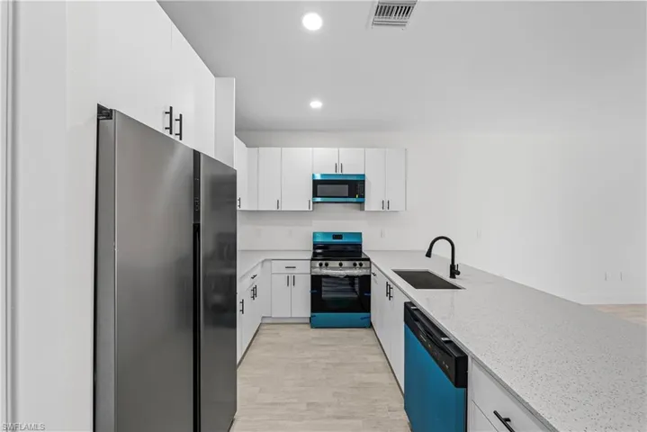 Kitchen featuring stainless steel appliances, white cabinetry, light stone counters, recessed lighting, and light wood-style floors