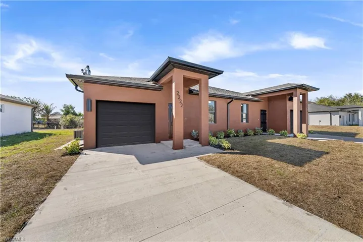 View of front of house featuring a front lawn, an attached garage, stucco siding, and concrete driveway