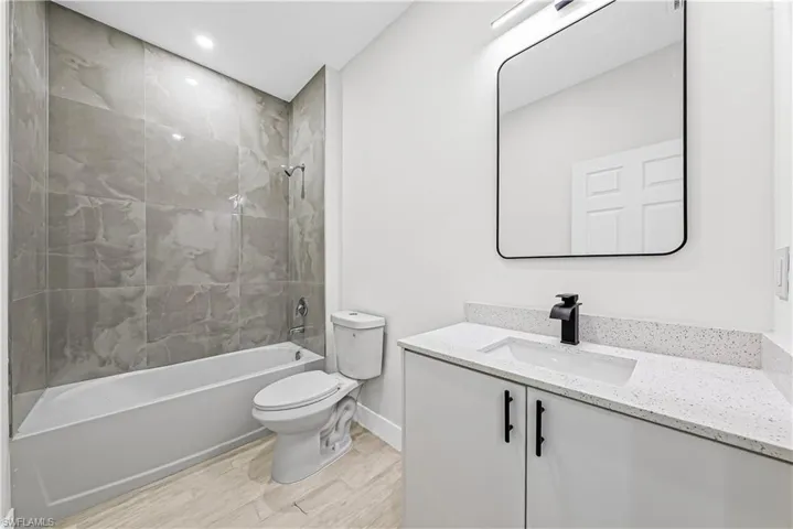 Bathroom featuring vanity, light wood-type flooring, tub / shower combination, and recessed lighting