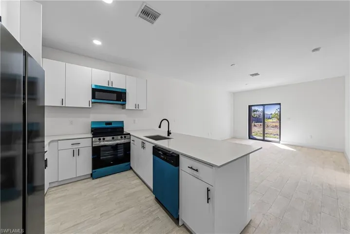 Kitchen with stainless steel electric range, freestanding refrigerator, white cabinets, a peninsula, and dishwasher