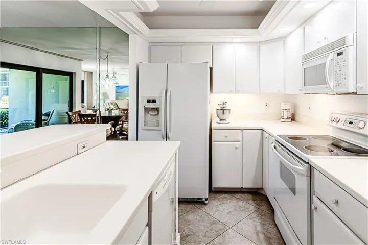 Kitchen with white appliances, white cabinetry, light countertops, and light tile patterned floors