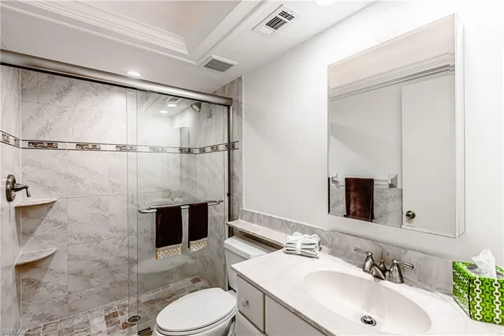 Bathroom with a stall shower, toilet, vanity, recessed lighting, and ornamental molding