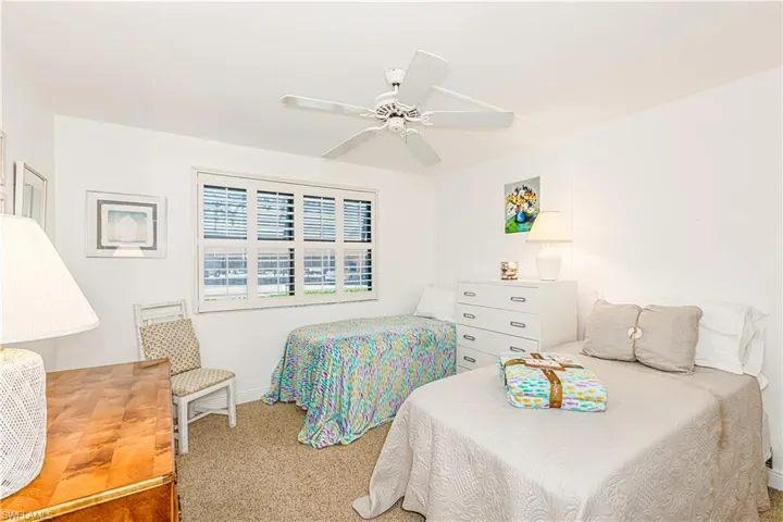 Carpeted bedroom with ceiling fan and baseboards