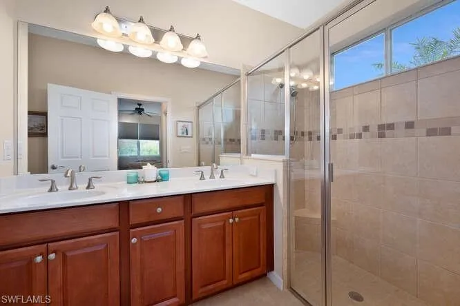 Bathroom featuring vanity, a shower with door, and ceiling fan