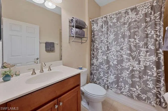 Full bathroom featuring tile patterned floors, vanity, shower / bath combination with curtain, and toilet