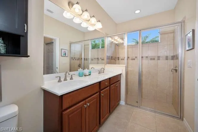 Bathroom with tile patterned floors, vanity, a shower with shower door, and toilet