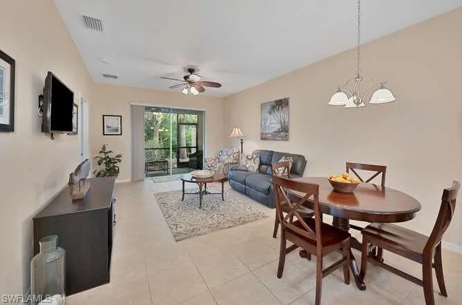 Dining space featuring light tile patterned floors and ceiling fan with notable chandelier