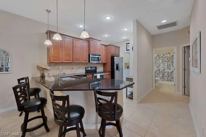Kitchen featuring kitchen peninsula, stainless steel appliances, pendant lighting, a breakfast bar area, and light tile patterned flooring