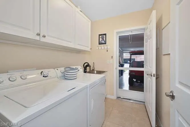 Clothes washing area featuring cabinets, separate washer and dryer, sink, and light tile patterned floors