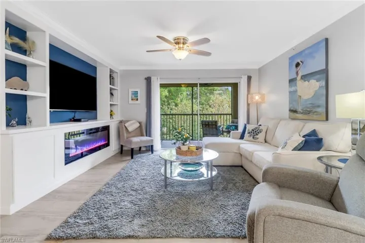 Living room with built in features, and ceiling fan