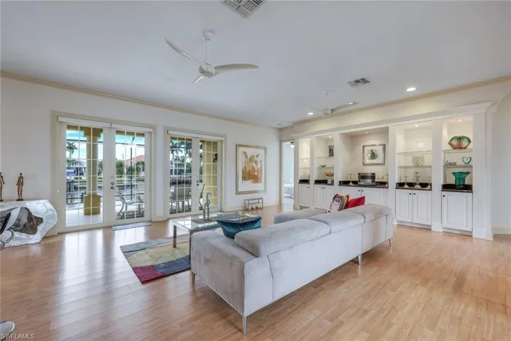 Living room featuring ceiling fan, crown molding, light hardwood / wood-style floors, and french doors