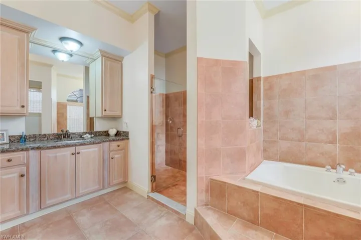 Bathroom featuring tile patterned floors, vanity, shower with separate bathtub, and ornamental molding