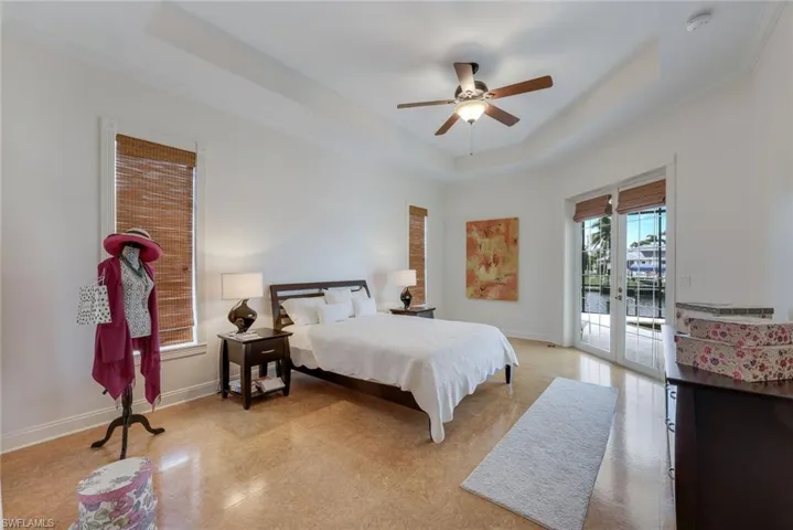 Bedroom with access to exterior, a tray ceiling, ceiling fan, and ornamental molding