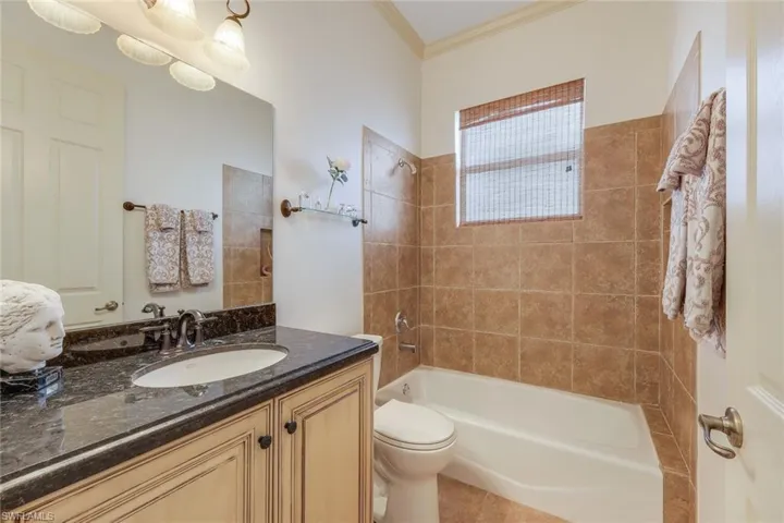 Full bathroom featuring tiled shower / bath combo, tile patterned floors, toilet, vanity, and ornamental molding