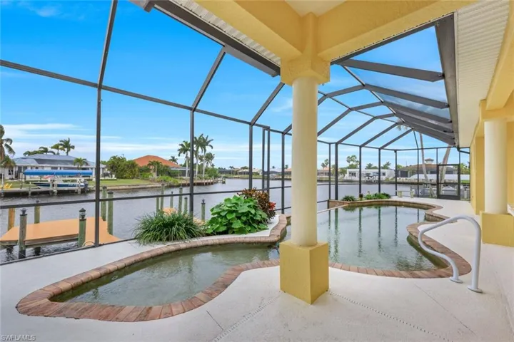 View of swimming pool with a water view, a dock, a lanai, and a patio area