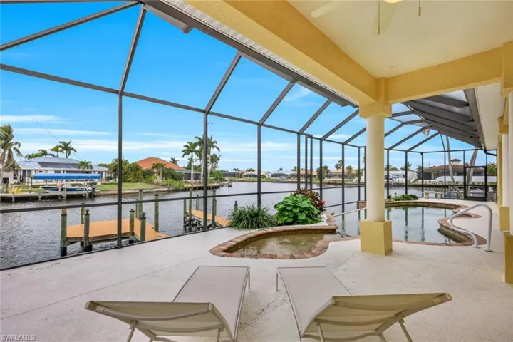 View of patio / terrace with glass enclosure, a water view, ceiling fan, and a dock