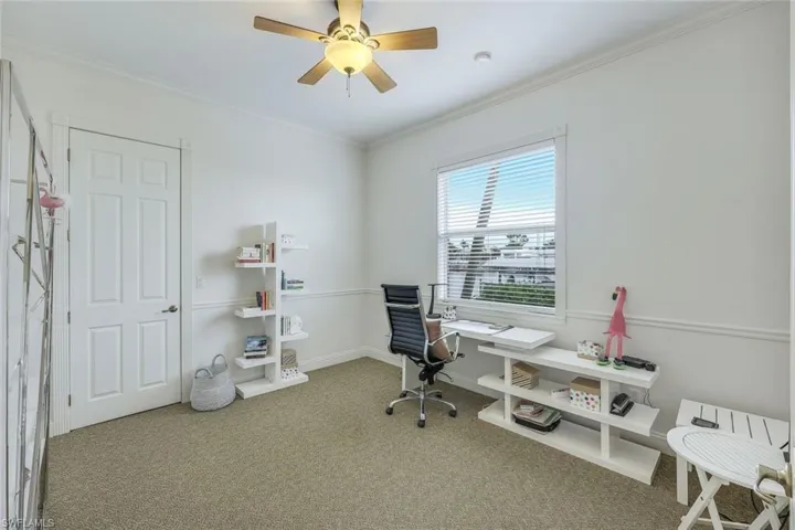 Carpeted home office featuring crown molding and ceiling fan