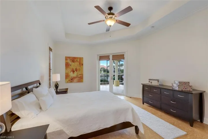 Carpeted bedroom with ceiling fan, access to exterior, a tray ceiling, and french doors
